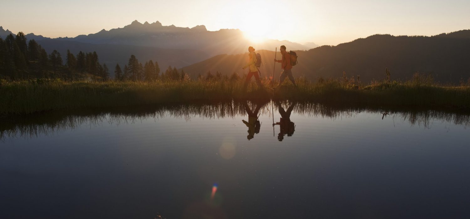 Austria, Salzburg, Couple walking near mountain lake at sunrise
